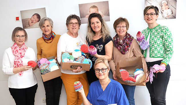 v.l. Claudia Duckeck vom Klinikum Traunstein, Christa Moser, Irmi Bienert, Tatjana Weihnacht, Stephanie Riedl, Rodica Onaci von der Christlichen Frauenbewegung Eggstätt. Vorne Cristina Cotoros vom Klinikum Traunstein, bei der Übergabe der Mützchen 